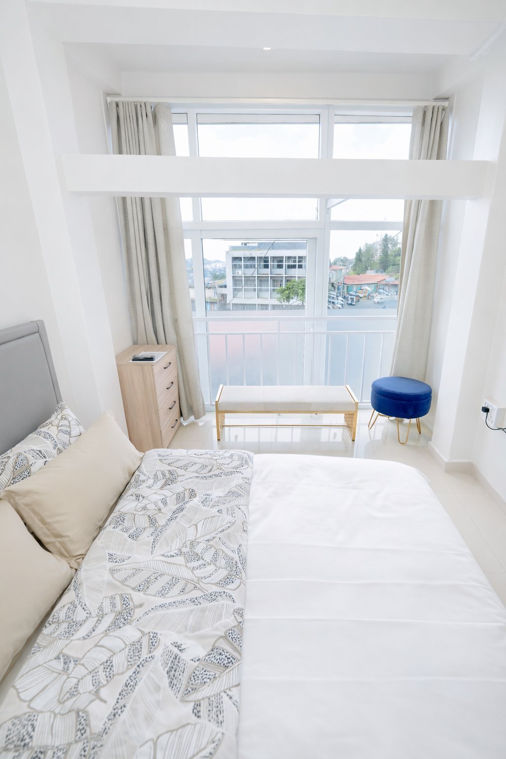 Deluxe Room — bright bedroom with city view and balcony